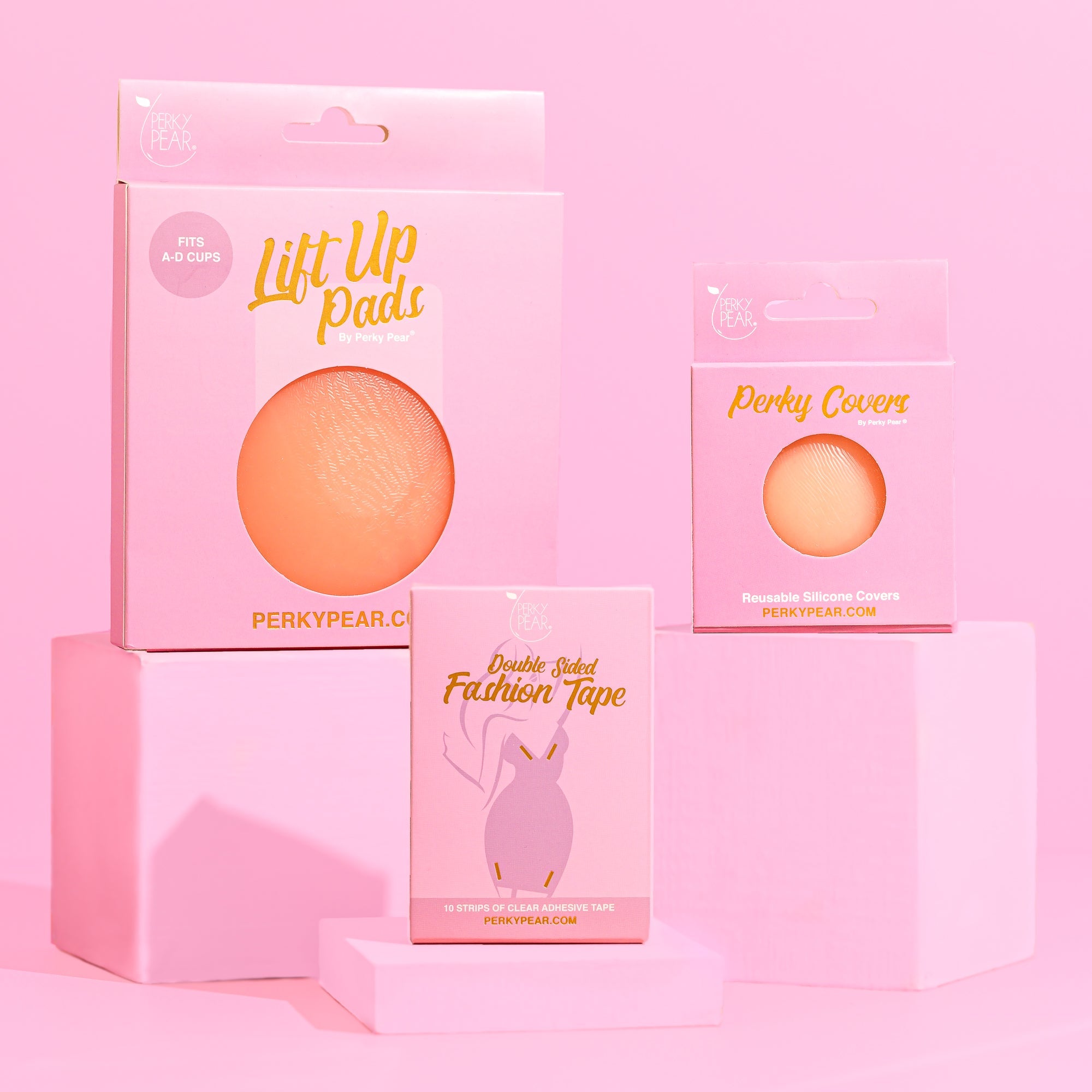  3 pink boxes containing boob tape, lift up pads and nipple covers - all pink boxes with pink background 