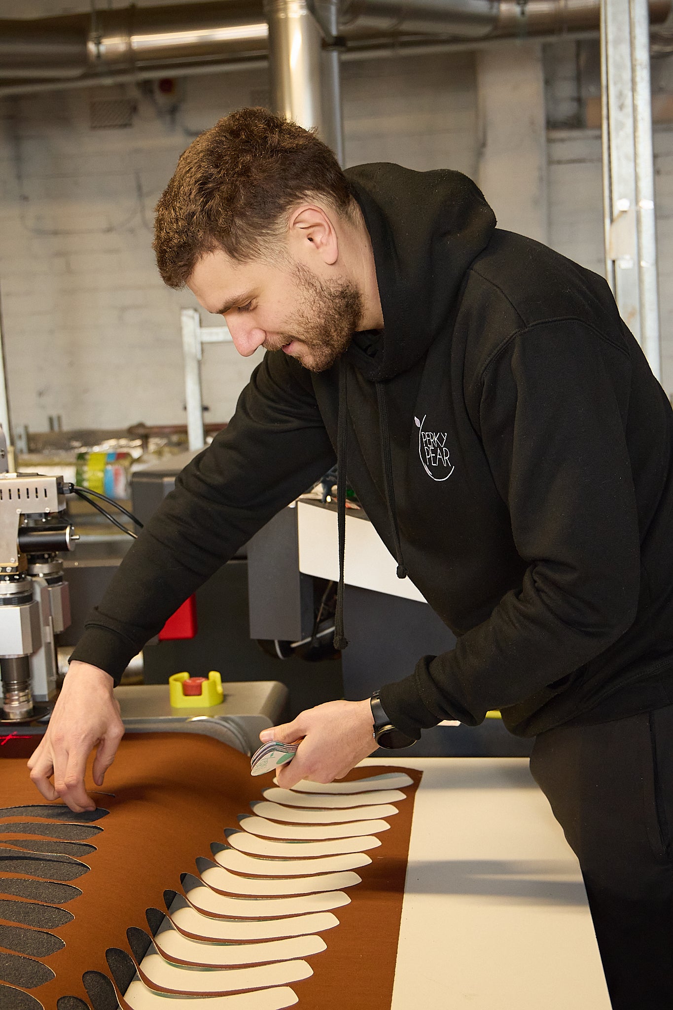 Man in a black hoodie working with dough in a workstation setting