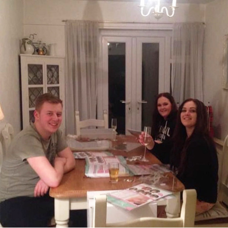 Three people sitting around a dining table in a home setting.

